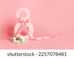 Small photo of Paper cut eight with ribbon on pink background. Postcard March 8 on a pink background