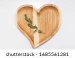 handmade wooden heart-shaped plate with green twig on the table