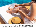 Small photo of Young woman applying sunscreen lotion at swimming pool to take care of her skin, Summer vacation concept