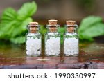 Three bottles of homeopathy globules. Bottles of homeopathic granules. Medicinal herbs on background. Homeopathy medicine concept. 