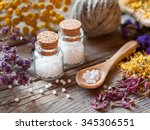 Bottles of homeopathy globules, wooden spoon and dry healthy herbs. Selective focus.