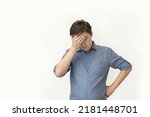 Small photo of young attractive man in a blue shirt on a white background holds his head, the concept of a problem and a difficult task, business. predicament fear and confusion