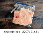 Thinly Pounded Chicken Breast Cutlets in a Plastic Bag: Overhead view of thinly pounded chicken cutlets with a meat mallet