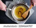Small photo of Brown Butter in a Stainless Steel Skillet with a Wooden Spatula: Overhead view of browned butter being stirred in a frying pan