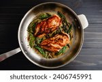 Chicken Breasts with Fresh Sage in a Stainless Steel Skillet: Marinated chicken breasts and fresh sage leaves frying in a large pan