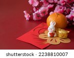 Chinese New Year of the rabbit festival concept. Mandarin orange, red envelopes, rabbit and gold ingot decorated with plum blossom on red background. 