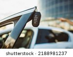 The concept of selling the purchase of leasing or renting a new car. Close-up of a car key hanging on the edge of an open vehicle door
