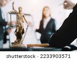 statue of justice with scales and auction hammer, the team meeting at the law firm behind the concept of in office law.