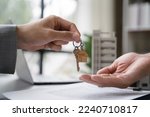 home loan officer gives the house keys to the client after signing a real estate contract with an approved mortgage application regarding the offer of mortgage loans and home insurance.