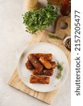 Small photo of Traditional south european skinless sausages cevapcici made of ground meat and spices on white plate on light wooden board, with thyme and watercress salad