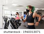 Small photo of Two fit woman running on treadmill wearing face masks. Abiding by pandemic rules of social distancing, wearing of face masks and to sanitize hands. To prevent the spread of the Coronavirus disease