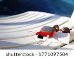Red music portable speaker is charged from the power bank via usb on a deck chair near the pool. Concept is always in touch, travel gadgets, external battery for a smartphone. Place for text. Flatlay