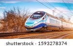 Small photo of Modern high speed aerodynamic streamlined electric train on rail during sunset passing by with motion blur.
