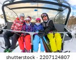 Family riding ski lift cable car on winter vacation skiing. Family on winter vacations ski trip taking selfie on ski lift with amazing mountain view of the ski resort and slopes. Active Family