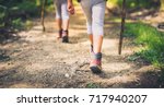 Children hiking in mountains or forest with sport hiking shoes. Girls or boys are walking trough forest path wearing mountain boots and walking sticks. Frog perspective with focus on the shoes.