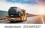 Small photo of A tow truck on the public road. A tow truck with a broken car on a country road. Tow truck transporting a car on the highway. Car service transportation concept.