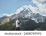 Small photo of Amidst the Silence of the Alps. A Hiker’s Pause Amidst Majestic Peaks with Snow-Capped Mountains and a Clear Sky as Backdrop. Hiker with pickaxe view from the rear.