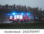 Small photo of An emergency vehicle drives fast on a road. a firetruck carrying firefighters and fire equipment are on their way to a fire or an accident. The siren sounds as the vehicle moves through the traffic