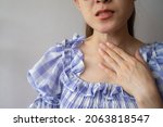 Small photo of Close up of woman touching her neck caused of having sore throat problem. A sore throat is a painful, dry, or scratchy feeling in the throat.