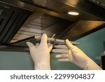 Small photo of Someone hands trying to removing a filters from cooker hood for cleaning it. Clean your filters every two to three months, depending on your cooking habits.