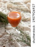 Small photo of Carrot orange juice in a vintage glass with heather plant near on vintage gauzy textile, closeup, vertical, copy space, art deco food and drink concept