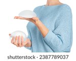 Woman holding and squeezing round implants on white background with clipping path. Mammoplasty and plastic surgery.