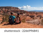 Small photo of Sitting couple enjoying scenic aerial view from Fairyland hiking trail on massive hoodoo sandstone rock formations, Bryce Canyon National Park, Utah, USA. Unique natural landmark in barren landscape