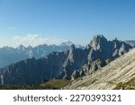 Panoramic view on Italian Dolomites. Endless, high and sharp mountains from each side. The peaks are shrouded in morning haze. Narrow pathway going along the mountain slope. Remote and isolated place