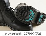Small photo of boots with studded soles, winter or demi-season shoes made of black leather with special retractable studs on the sole