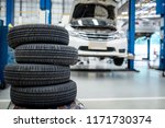 Small photo of 4 new tires that change tires in the auto repair service center, blurred background, the background is a new car in the stock blur for the industry, a four-wheeled tire set at a large warehouse