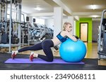 Beautiful woman is doing exercises in a fitness room with ball.