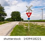 Small photo of rural railroad crossing in the country without warning lights or crossing arms, only a yield sign and railroad crossing sign