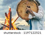 shaman plays drums near the big fire on the sky background