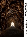Small photo of Man silhouetted with arms spread in an empty decommissioned railroad tunnel