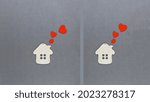 Small photo of Two toy wooden houses with red hearts flying out of the pipes. Concept of the world of love and good neighborliness. Love house concept.