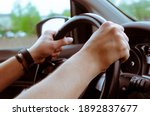 The steering wheel of the car is in the hands of a man while traveling