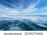 Unusual winter landscape of frozen Baikal Lake on February day. Above icy endless desert, beautiful stratus clouds adorn the blue sky. Natural cold background. Winter travel and outdoor recreation