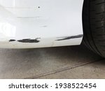 Small photo of Traces of the front bumper of a white car that collides with the curb or obstacles that are so low that the white has come off (scrapes) and see the black fiber inside.