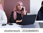 Small photo of Woman wearing head scarf at office with workmates. Middle Eastern lady wearing ethnic hair veil hair together with workmate wearing Kandura and Abaya