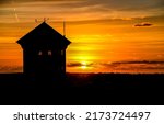 Silhouette of a lonely house against the sunset. Lonely house at sunset. Sunset house view. House at sunset