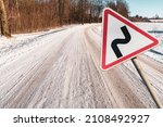 Small photo of Double bend ahead right then left road sign in winter land. Warning on the way. Double bend signification. Warning traffic sign next to the winter route.