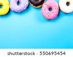 Colorful round donuts on blue background. Flat lay, top view.