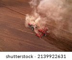 Small photo of Tactor with disk harrow on plowing field. Cultivated land and soil tillage. Tractor with disc cultivator on land cultivating. Agricultural tractor on cultivation field. Plough plowed in agriculture.