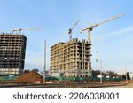 Сonstruction site with tower cranes on building construction. Builder on formworks. Cranes on pouring concrete in formwork. Tower cranes on construction in built environment. Buildings renovation.