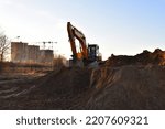 Small photo of Excavator on earthmoving on sunset. Loader on excavation. Excavator digs gravel. Earth-Moving Heavy Equipment for Construction. Earth mover ar construction site. Backhoe Loader. Road construction.