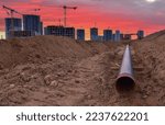 Small photo of Sewer pipes laying. Sanitary drainage, external sewage. Tower crane on building construction. Excavator dig trench on construction site. Stormwater dig and pipe underground. Water infrastructure.