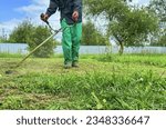 Small photo of Gardener mows weeds grass. Man cutting grass in yard by using string trimmer. Worker lawn mower cutting green garden. Lawn mowing machine. Grass Trimmer and Grass Cutter. lawn maintenance service.
