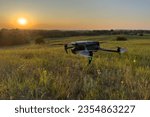 Drone flying in field at sunset. Inspection of a farmer's field with a drone. Drone flying in air over an agricultural field. Copter for photography and video