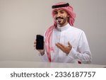 Small photo of A Saudi character holding a phone sitting in the office on a white background