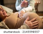 Small photo of Cropped image of smiling pregnant woman and midwife at home. Woman in casual clothes lying on bed, midwife holding hand. Pregnancy, medicine, home birth concept